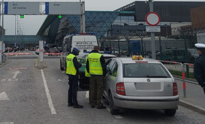 policjanci wspólnie z funkcjonariuszami  ITD i SG kontrolują pojazd - przewoźnika aplikacji mobilnej, w tle budynek lotniska (2)
