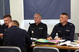 policjanci na sali odpraw siedzący na spotkaniu roboczym w sprawie Odblaskowej szkoły