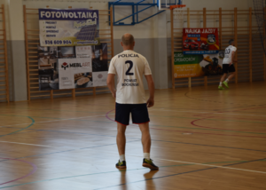 Zawodnicy policyjnej drużyny. Na pierwszym planie zawodnik w koszulce z numerem 2 i napisem POLICJA  oraz POWIAT BOCHEŃŚKI