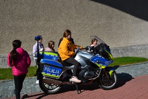 dziewczynka w żółtej kurtce siedzi na służbowym motocyklu, obok inne dzieci