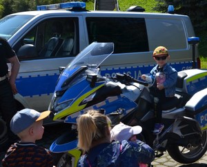 chłopiec na policyjnym motocyklu, w ręku trzyma puszkę na datki na leczenie małej Wiktorii