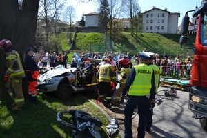 pokaz usuwania skutków wypadku - rozbity samochód, strażacy, policjanci, ratownicy medyczni, w tle uczestnicy pikniku
