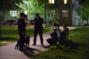 policjanci i strażnik miejski kontrolują osoby siedzące na ławkach