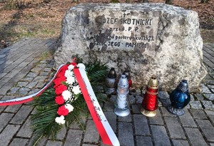obelisk poległego w wlace policjanta, przy którym słożona jest wiązanka z biało - czerwonych kwiatów