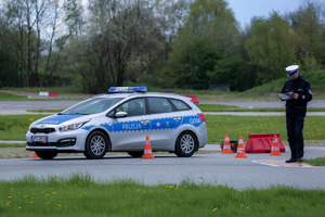 Policjant zapisuje wynik. Obok stoi radiowóz