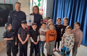 policjanci na pamiątkowym  zdjęciu z przedszkolakami i otrzymanym Aniołem Wdzięczności