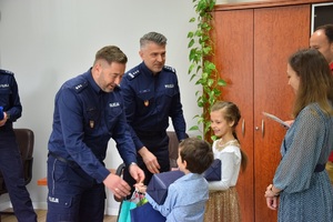 komendant Miejski i jego zastępca wręczają dzieciom nagrody