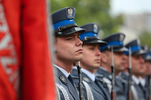 Policjanci kompanii honorowej na pierwszym planie fragment sztandaru