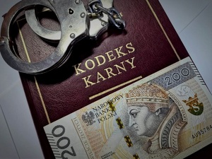 banknot 200 zł na kodeksie karnym i kajdanki