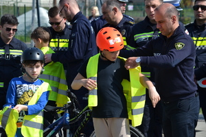 Gruziński policjant pomaga ubrać się chłopcu w kamizelkę odblaskową