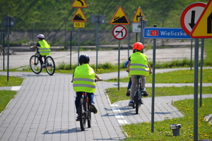 Rowerzyści ubrani w kamizelki odblaskowe poruszający się po miasteczku ruchu drogowego