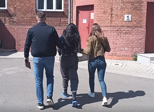 nieumundurowana policjantka i policjant prowadzą zatrzymaną do budynku komendy