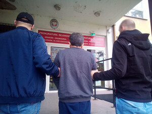 dwóch policjantów nieumundurowanych prowadzi zatrzymanego do budynku prokuratury