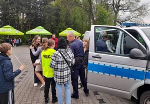 Piknik parafia Osiek dzielnicowy rozmawia z grupą dzieci i młodzieży przy radiowozie