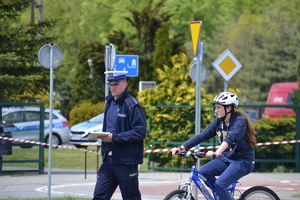 Zawodnik z  policjantem na rowerze na miasteczku ruchu drogowego