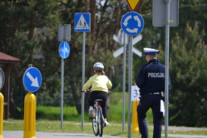 Zawodnik z policjantem na rowerze na miasteczku ruchu drogowego ze znakami drogowego