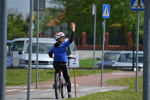 Zawodnik z uniesioną ręką na rowerze na drodze na miasteczku ruchu drogowego
