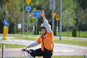 Zawodnik z uniesioną ręką na rowerze na miasteczku ruchu drogowego