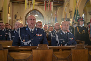 siedzący w ławce kościelnej zastępca komendanta wojewódzkiego policji w Krakowie oraz komendant powiatowy policji w Brzesku, w tle inni uczestnicy mszy