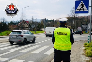 policjant stojący przy przejściu dla pieszych i jadące na drodze samochody