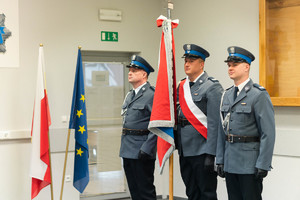 poczet sztandarowy Komendy Powiatowe Policji w Chrzanowie trzymany przez umundurowanych funkcjonariuszy, w tle flaga Polski, flaga Uni Europejskiej