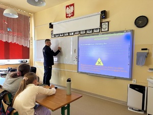 Policjant rysuje na tablicy w sali lekcyjnej szkoły