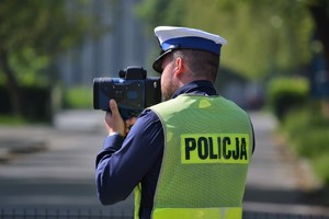 Policjant ruchu drogowego mierzy prędkość ręcznym miernikiem prędkości