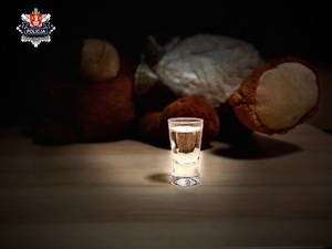 napełniony kieliszek za którym leży pluszowy miś