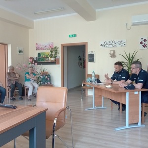 policjanci przy stoliku w pomieszczeniu a przed nimi seniorzy