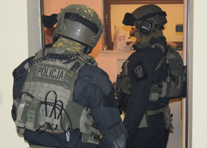 dwóch policjantów z podododziału kontrterorystcznego policji stojących w drzwiach mieszkania