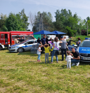 Policyjne radiowozy, policjanci, wóz strażacki oraz uczestnicy biorący udział w akcji