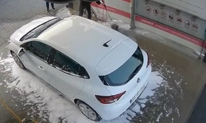 Screen z monitoringu myjni samochód  obok skulony pies i mężczyzna z lancą skierowaną w stronę psa