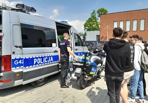 grupa młodzieży przy motocyklu i radiowozie obok stoi policjant