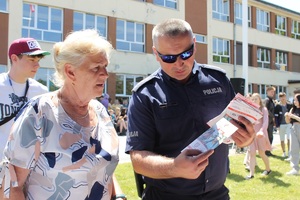 policjant wręczający kobiecie ulotkę o akcji aktywny i bezpieczny senior