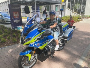 dziecko w czapce policjanta ruchu drogowego siedzi na policyjnym motocyklu