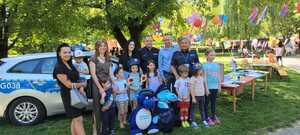 uczestnicy pikniku na pamiątkowym zdjęciu przy radiowozie policyjnycm z policjantami i maskotkami policyjnymi