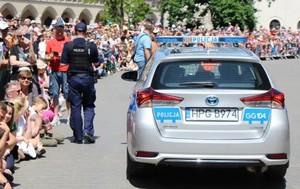 policjant obok radiowozu oraz osoby zgromadzone na krakowskim Rynku Głównym