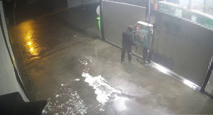 mężczyzna włamujący się do urządzenia płatniczego na terenie myjni samochodowej samoobsługowej widoczny tyłem