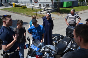 policjant stojący obok motocykla, wokół wychowankowie Domu Pomocy Społecznej i siostry zakonne