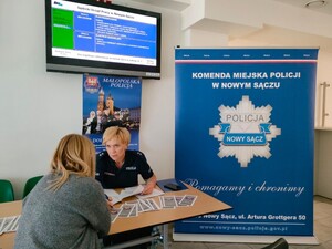 policjantka i kobieta rozmawiają przy stole, na którym położone są ulotki