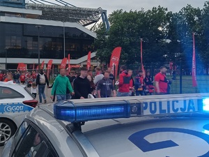 policyjne sygnały świetlne, w których tle widać kibiców opuszczających rejon stadionu Wisły Kraków
