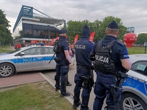 umundurowani policjanci stojący obok radiowozów obesrwują przemieszczjących się kibiców przy stadionie Wisły Kraków