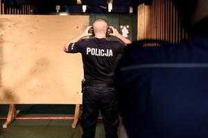 Umięśniony policjant zakłada słuchawki wygłuszające przed strzelaniem