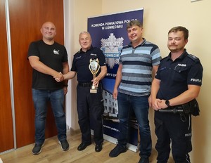KPP Oświęcim. Komendant gratuluje trzem  policjantom w tle rollup