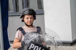 dziecko z policyjną tarczą w kasku