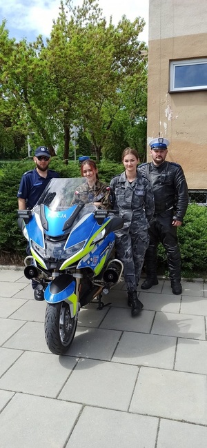 Wspólne zdjęcie policjantów i licealistek przy motocyklu.