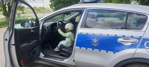 Dziewczynka siedząca w radiowozie, trzyma kierownicę