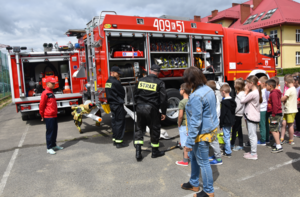 Wóz strażacki, strażacy oraz ucznioiwe biorący udział w prelekcji