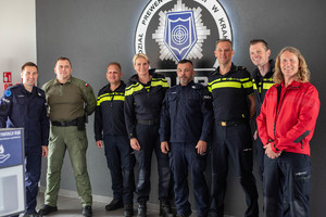 Zdjęcie grupowe Polskich i Holenderskich policjantów. Z tyłu widoczne jest zdjęcie Oddziału Prewencji Policji w Krakowie