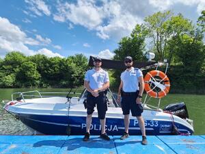 Dwóch policjantów stoi na pomoście przed policyjną łodzią